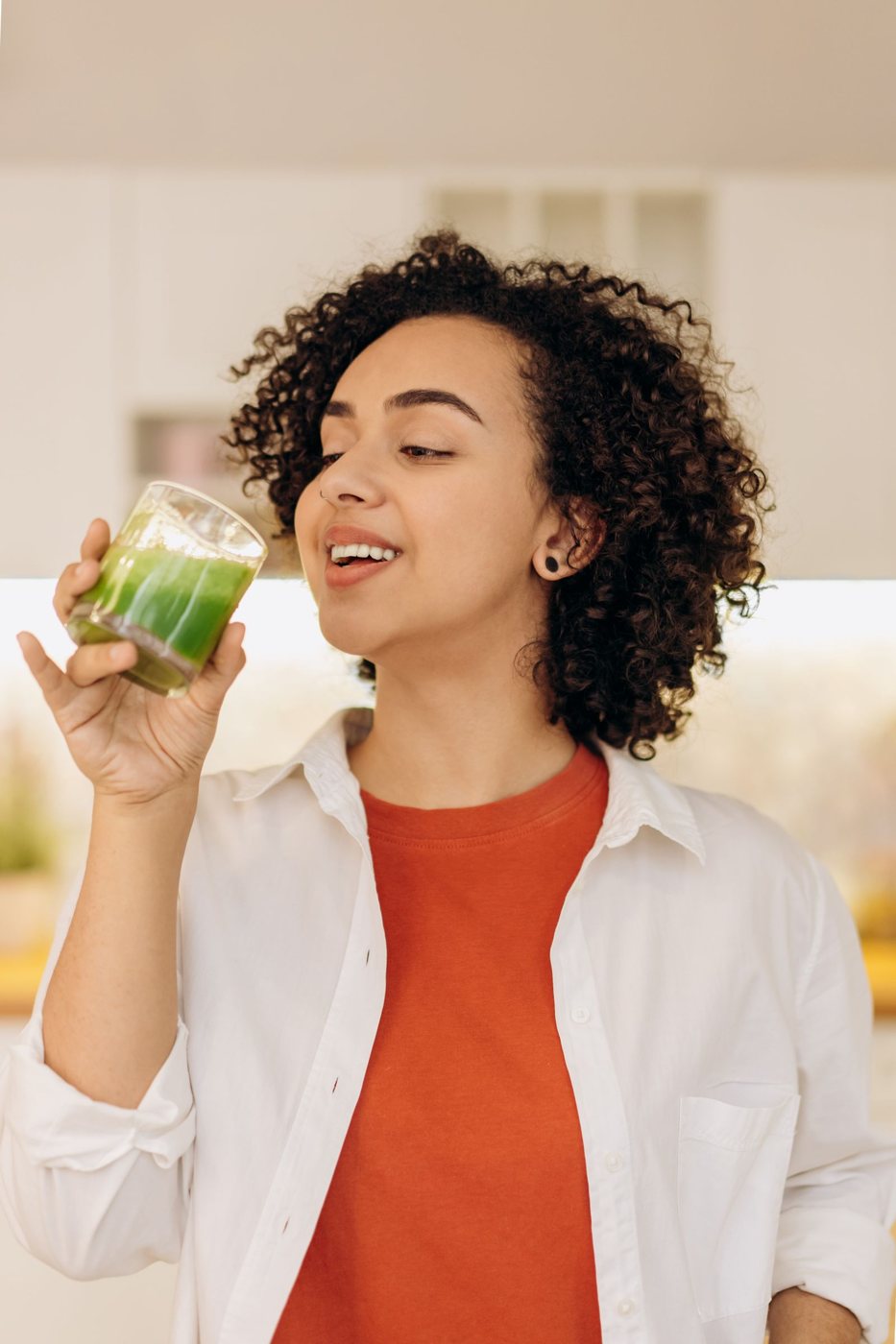 Mulher a beber um batido verde na cozinha