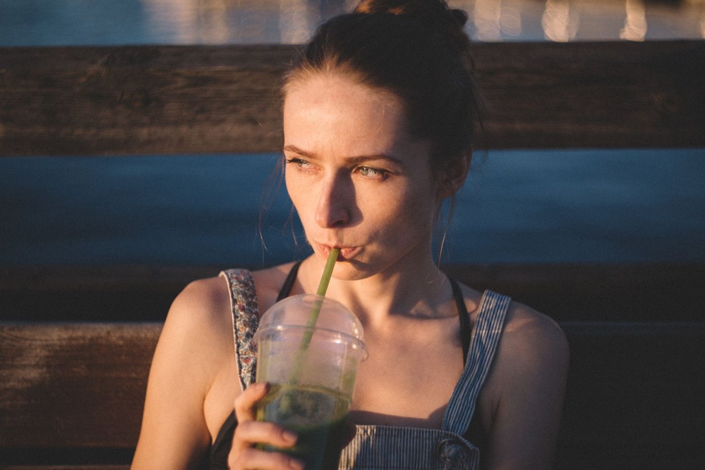 Mulher a beber uma bebida com palhinha ao fim da tarde